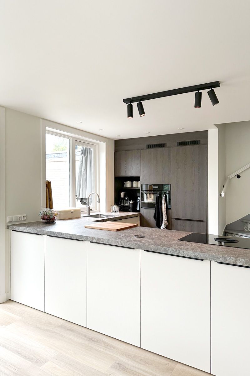 Moderne keuken in jaren 30 woning met lichtgrijs werkblad en ingebouwde kast.
